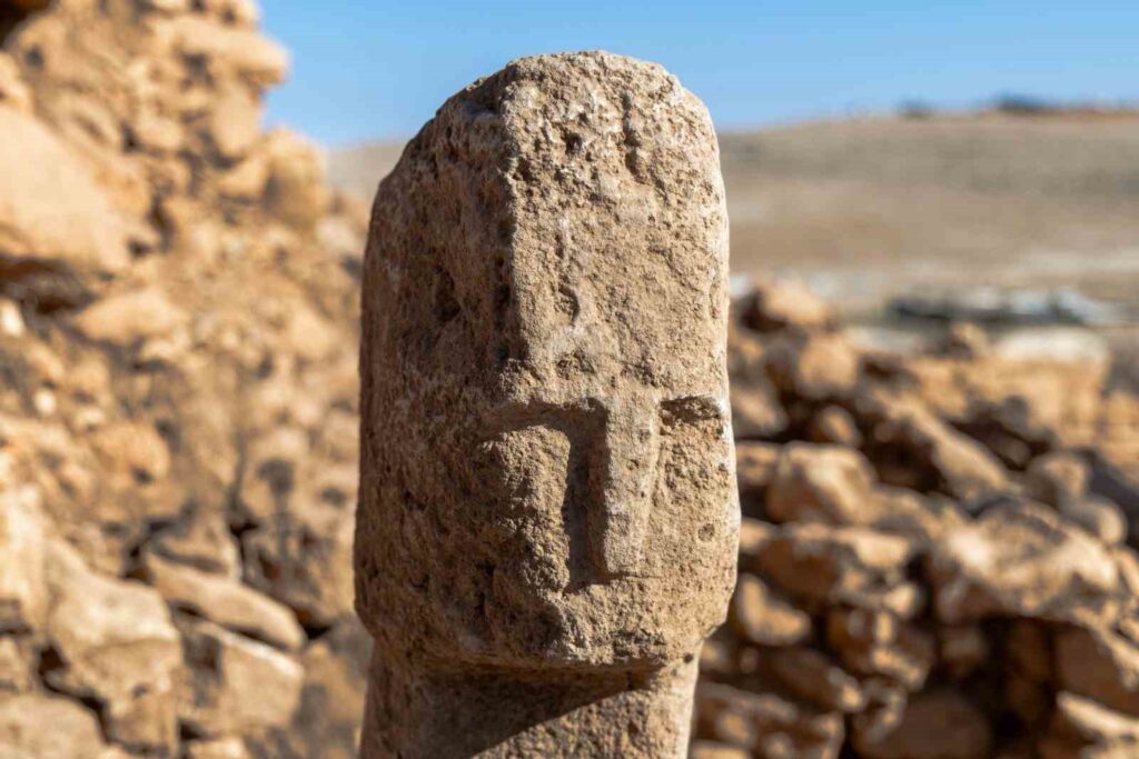 Archaeologists have uncovered a T-shaped pillar carved with a human face at the Neolithic site of Karahantepe in southeastern Türkiye — a discovery described as a first in human history.

The finding was announced by Minister of Culture and Tourism Mehmet Nuri Ersoy on his official X (Twitter) account, where he wrote:

“Karahantepe — A first in history! Within the scope of our Taş Tepeler Project, a T-shaped pillar with a human face has been unearthed for the first time.”

The discovery forms part of the Taş Tepeler (Stone Hills) Project, a long-term archaeological initiative led by the Turkish Ministry of Culture and Tourism, which explores the earliest stages of human settlement and symbolic expression in the Şanlıurfa region.

A Turning Point in Neolithic Symbolism

For decades, the T-shaped pillars of Göbeklitepe and Karahantepe have been interpreted as stylized human figures, primarily due to the carved arms and hands visible on many examples. Yet, this new pillar — the first to bear a carved human face — marks a major leap in understanding how early Neolithic societies perceived themselves.

The pillar’s face, featuring deep-set eyes, a pronounced nose, and sharp contours, resembles other human sculptures from Karahantepe. Experts say the find reflects not only the craftsmanship of early Anatolian communities but also their emerging capacity for abstract and self-referential thought.

From Symbol to Identity

Until now, these T-shaped monoliths were thought to serve either as structural elements or abstract human representations. The new find, however, provides the first direct depiction of the human visage, offering a rare glimpse into the earliest stages of self-image in human history.

Karahantepe and the Taş Tepeler Network

Dating back approximately 12,000 years, Karahantepe is one of several interconnected sites in the Taş Tepeler region, which also includes Göbeklitepe, Sefertepe, Sayburç, Harbetsuvan Tepesi, and Çakmaktepe. These settlements continue to reshape our understanding of humanity’s transition from nomadic life to organized, temple-centered communities.

Together, they position Anatolia as one of the earliest centers of symbolic architecture and spiritual innovation.